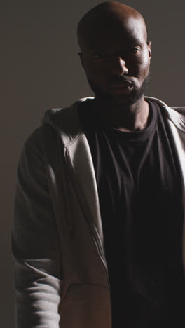 Vertical-Video-Studio-Vertical-Video-Portrait-Shot-Of-Male-Basketball-Player-Wearing-Tracksuit-Throwing-Ball-From-One-Hand-To-The-Other-Against-Dark-Background-1